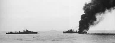HMS Fearless on fire with HMS Forester standing by.